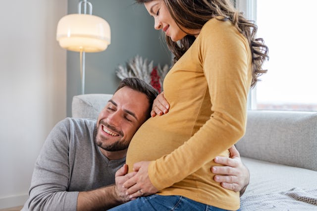 Happy man putting a head on a pregnant woman's belly. They are very happy and enjoy their love a lot...
