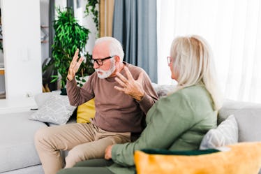 Senior heterosexual couple are quarreling while sitting on couch at home.