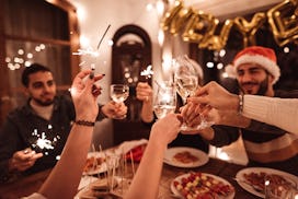 A group of friends toasts at dinner, in a story about new year's trivia questions and answers.