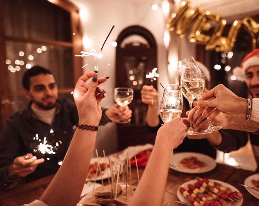 A group of friends toasts at dinner, in a story about new year's trivia questions and answers.