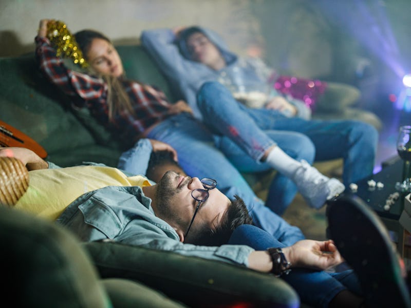 Group of wasted friends sleeping after party in the living room. Focus is on man in the foreground.
