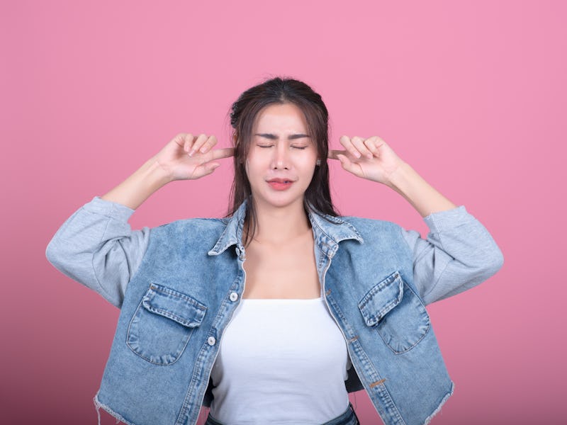 Confused woman puts her hands on the head, isolated on pink,Woman put her hand on her ears
