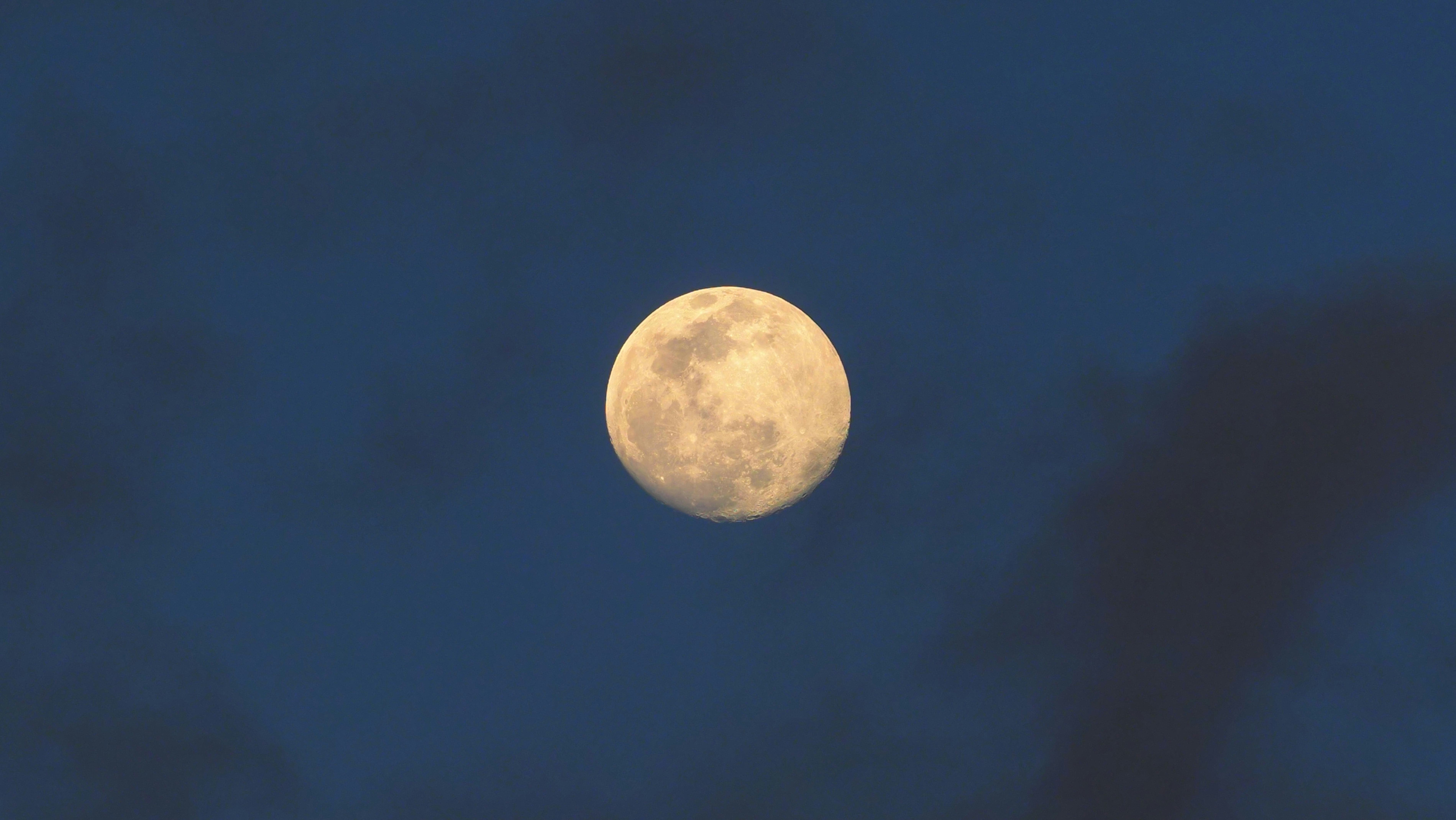 A superb image of the full moon and a few soft clouds patching the sky above.