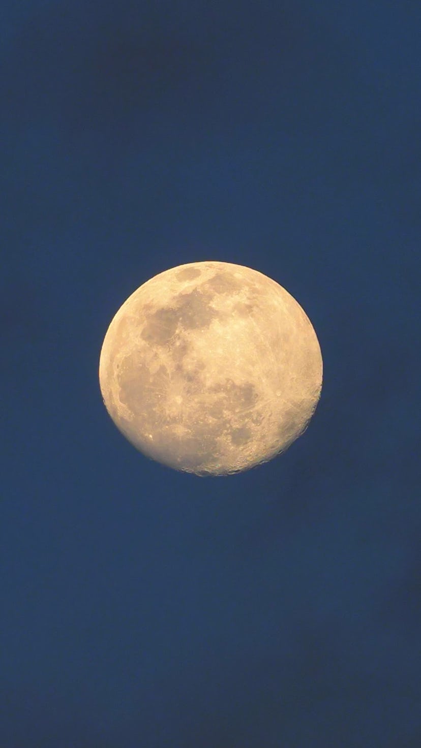 A superb image of the full moon and a few soft clouds patching the sky above.