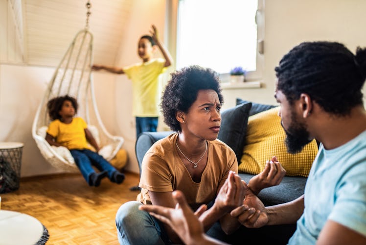 Worried African American parents arguing in the living room while with kids in the living room.