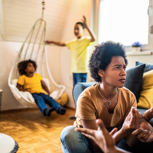 忧心忡忡的非裔美国父母在客厅和孩子们争吵。