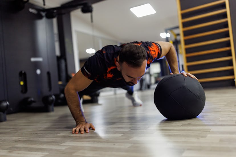 Sportsman doing push-ups with a medicine ball in the gym