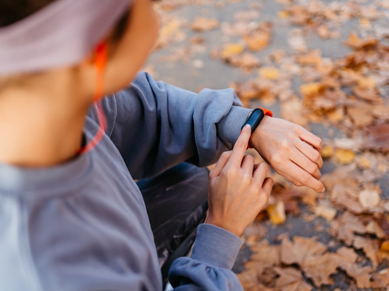 Beautiful young woman checking fitness activity on a smart watch after running in the public park.