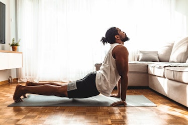 Indoor shot of handsome young man practicing yoga. Fitness man meditating with his eyes closed while...
