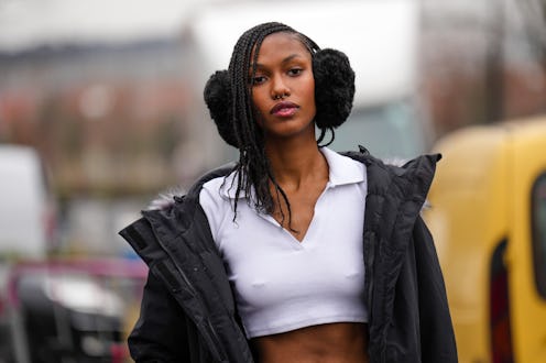 PARIS, FRANCE - MARCH 03: A model wears a black fluffy ear muff, a white zipper neck / polo cropped ...