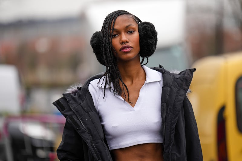 PARIS, FRANCE - MARCH 03: A model wears a black fluffy ear muff, a white zipper neck / polo cropped ...