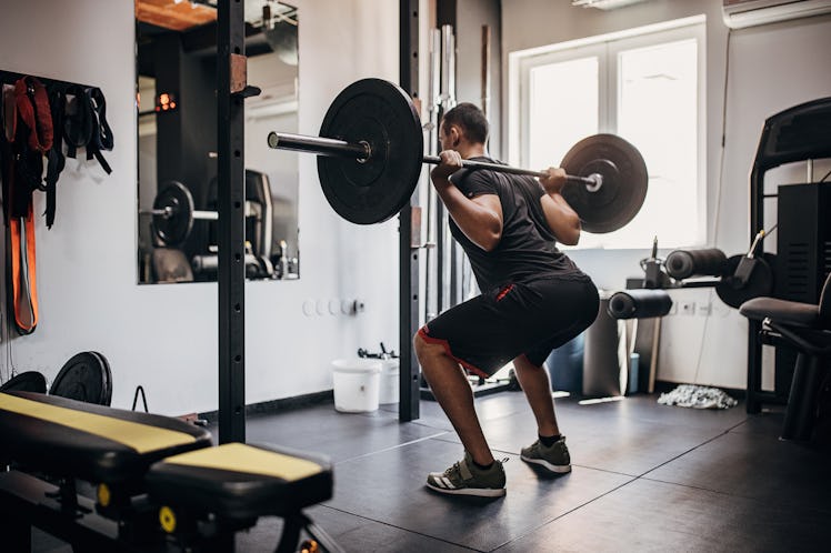 One man, fit young male exercising with weights in gym.