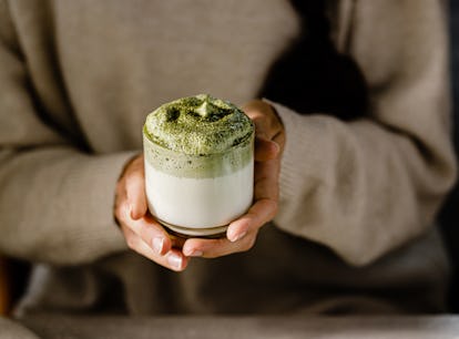 A woman holding a fresh Dalgona matcha latte glass, like Kourtney Kardashian's whipped matcha recipe...