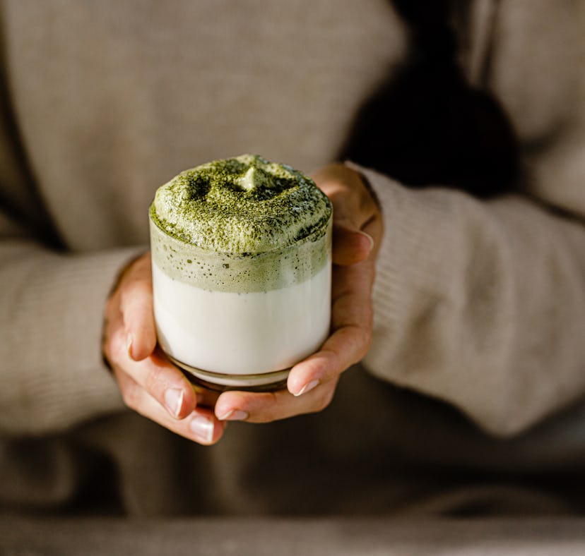 A woman holding a fresh Dalgona matcha latte glass, like Kourtney Kardashian's whipped matcha recipe...