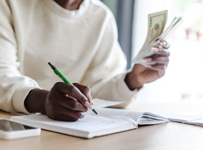 A woman holding money does the $10,000 in 3 months savings challenge from TikTok.