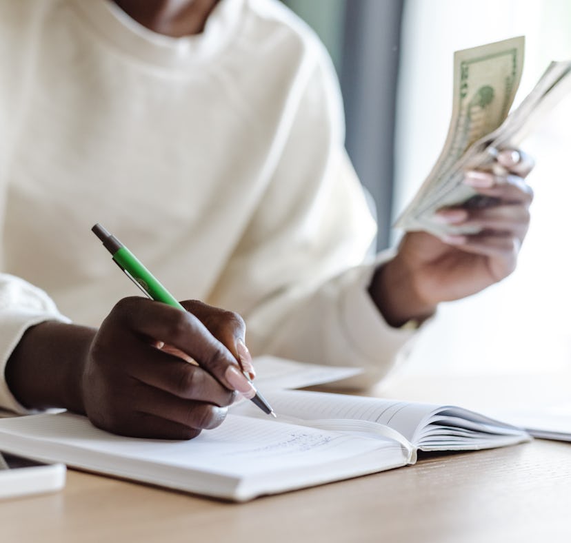 A woman holding money does the $10,000 in 3 months savings challenge from TikTok.