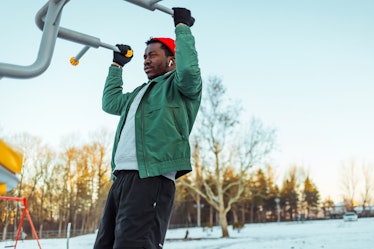 Young African Man doing pull ups at sunset,  exercising on winter day