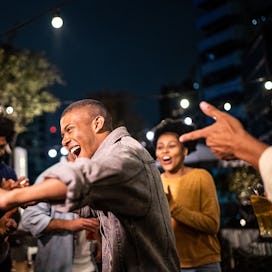 Happy friends dancing during party at night