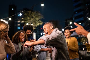 Happy friends dancing during party at night