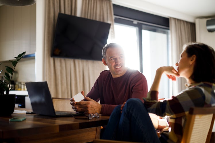 Woman pointing at something on laptop screen while looking at online banking with her hausband