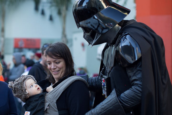 LOS ANGELES, CA - DECEMBER 12:  A baby looks up at David Baxter who is dressed as Darth Vader as fan...