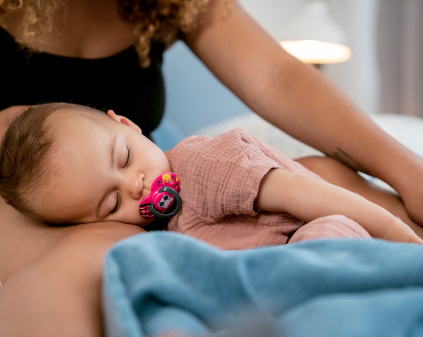 A mom pats her baby to sleep instead of using a plush fish that pats baby to sleep.