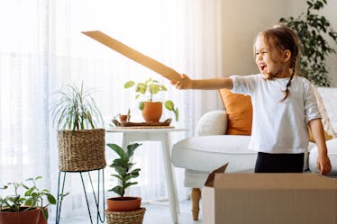 Playful childhood. Little girl having fun with cardboard box.