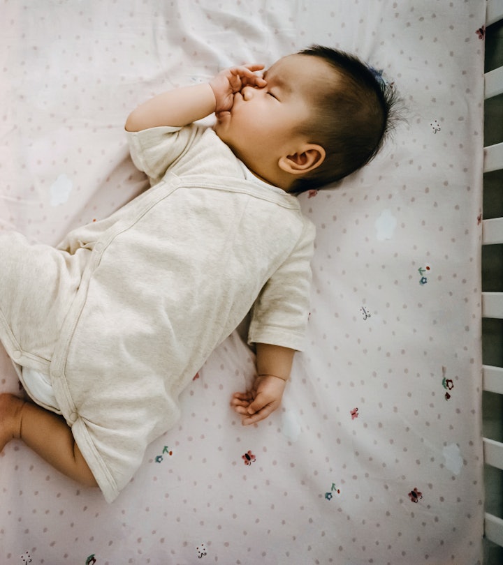 cute baby sleeping in a crib in an article about the Ferber method of sleep training