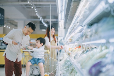 年轻的美籍华人家庭在超市冷藏区购买新鲜蔬菜。