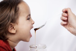 a kid eats honey in an article about honey for toddler cough honey for kids cough