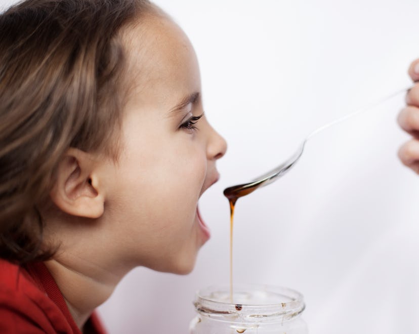 a kid eats honey in an article about honey for toddler cough honey for kids cough