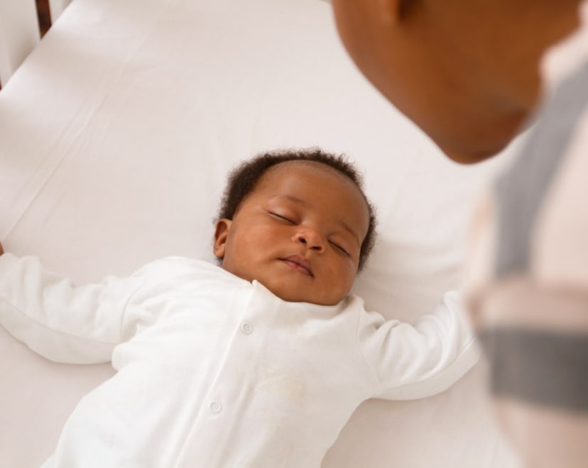 a baby sleeping in a crib in an article about the cry it out method of sleep training