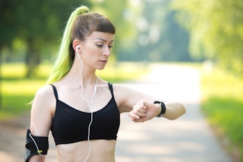 Young woman in sports clothing checking her heart rate on her smart watch. She is wearing sports clo...