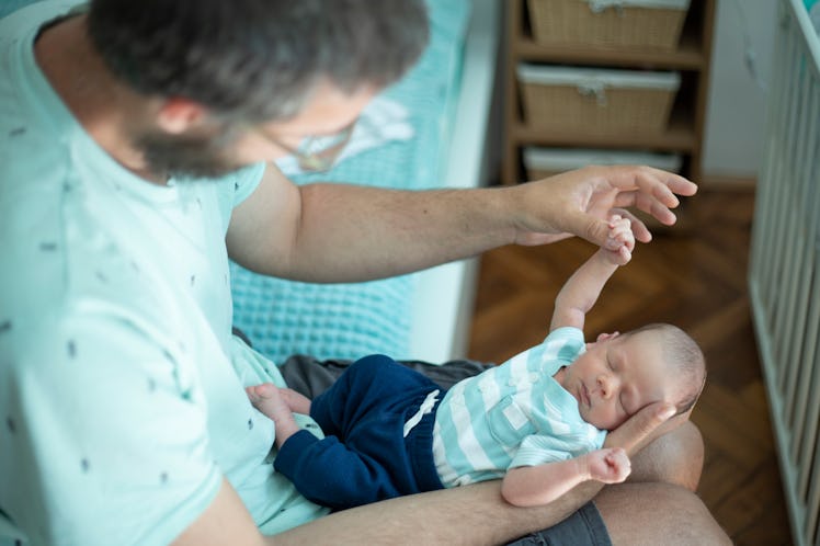 Young father holding his sleeping newborn baby boy.