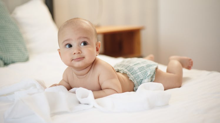 Adorable baby boy lying on stomach in bed
