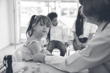 Doctor injecting vaccination in arm of asian little child girl