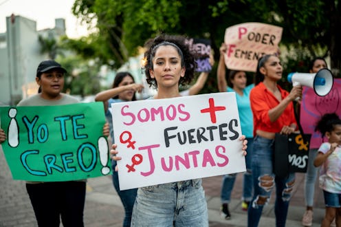 Portrait of mid adult protester woman holding a sign on a demonstration outdoors