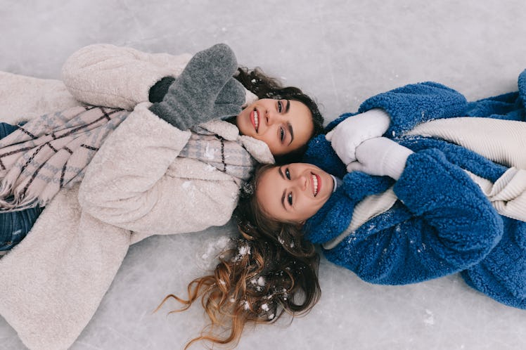 two young women smile as they lay down next to you in the snow and discuss how they will be affected...