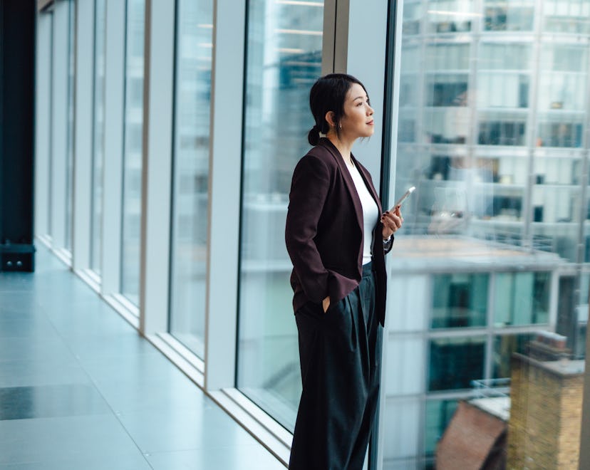 Woman in business setting looking out window, thinking about aquarius 2023 horoscope