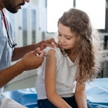Young  doctor vaccinating little girl. The bivalent vaccine is now available for kids as young as si...