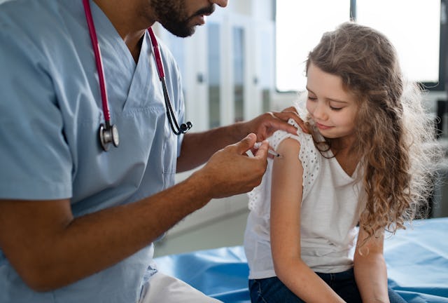 Young  doctor vaccinating little girl. The bivalent vaccine is now available for kids as young as si...