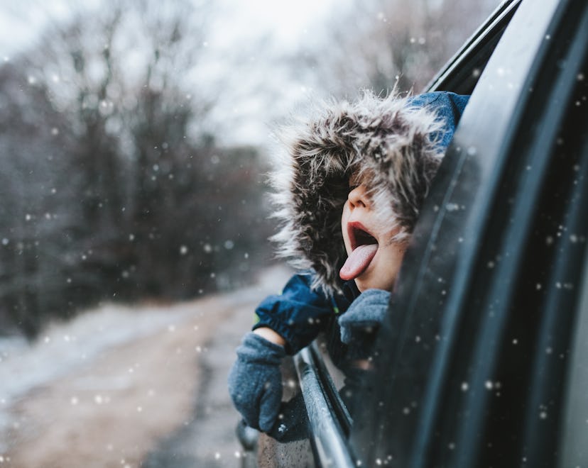 Boy on a road trip sticking his tongue out the window to catch snowflakes, in a story about tips for...