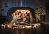 Happy mother sitting with her children and adopted children in a tent at home and having fun while r...
