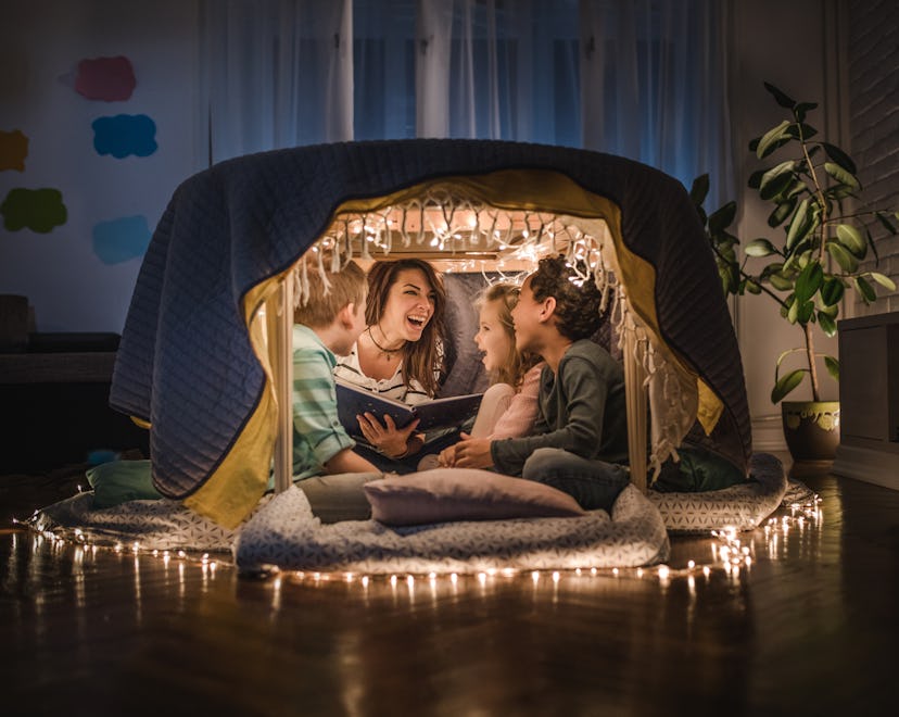 Happy mother sitting with her children and adopted children in a tent at home and having fun while r...
