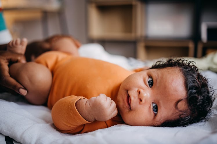 Portrait of a newborn baby lying on a bed in the living room