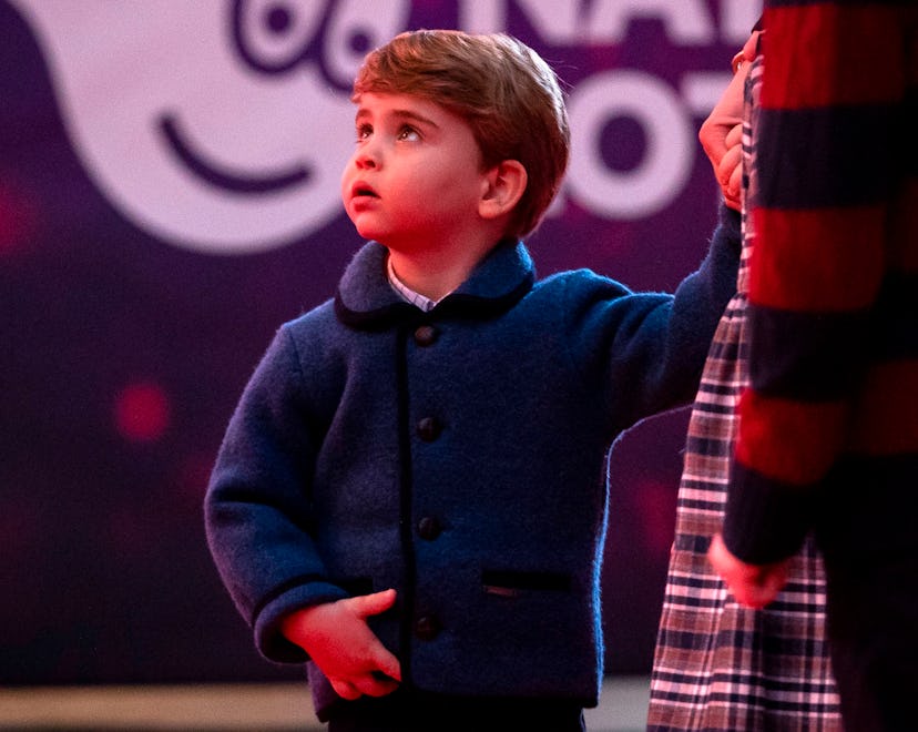 Britain's Prince Louis of Cambridge holds his mother's hand as they attend a special pantomime perfo...