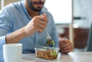 一个中东男人用叉子吃玻璃容器里的健康沙拉的手特写…