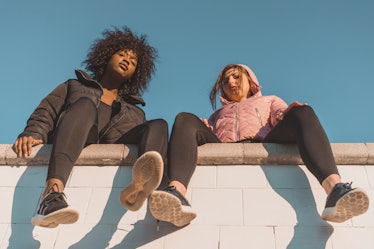 two friends sit on a wall and look down at a camera, as they discuss how the winter solstice will le...