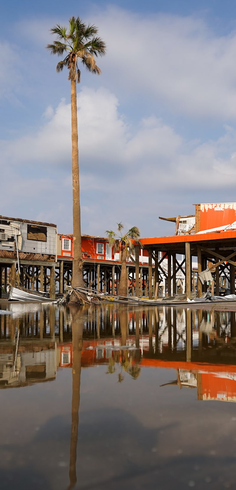 GRAND ISLE, LA - SEPTEMBER 3: Storm damaged houses are reflected in flood water after Hurricane Ida ...