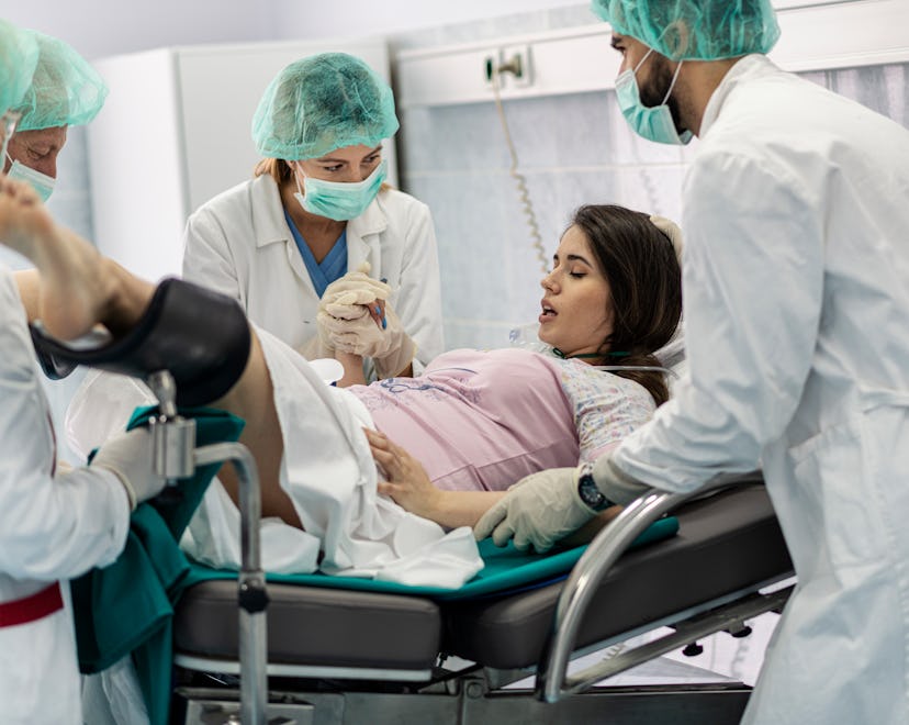 Obstetricians assisting in the hospital woman in labor pushes to give birth